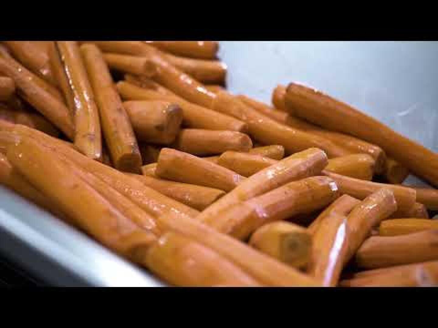 Ein Haufen geschälter Möhren liegt in einem Metallbehälter. Die Möhren sehen sauber und orange aus und sind bereit für die Weiterverarbeitung oder das Kochen.