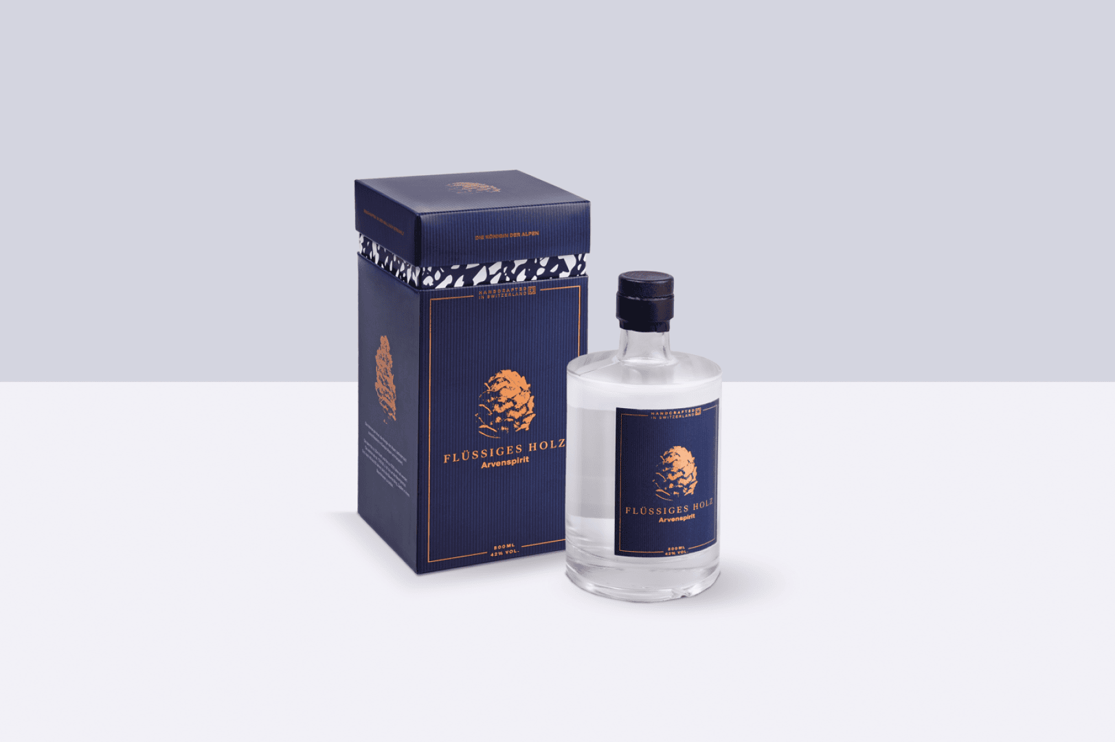 Eine klare Flasche Flüssiges Holz mit einem blau-goldenen Etikett steht neben der passenden blau-goldenen rechteckigen Schachtel auf einem hellen, minimalistischen Hintergrund.