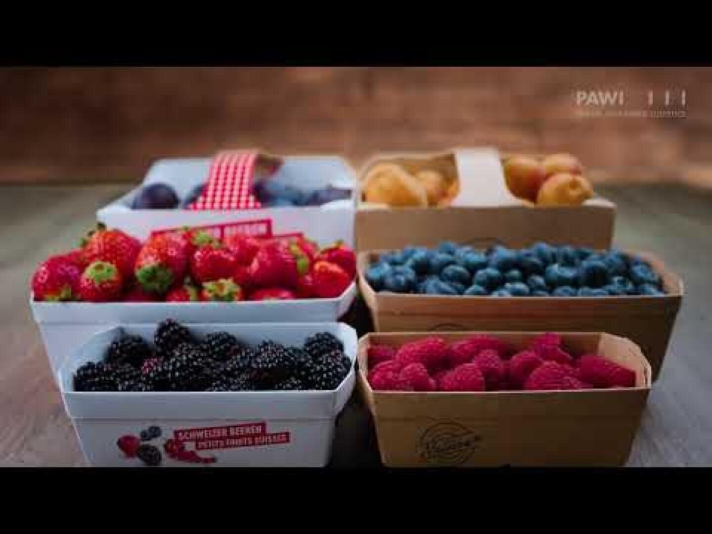 Six boxes of fresh fruit, including strawberries, blackberries, blueberries, raspberries and apricots, are arranged on a dark surface with a rustic wooden background.