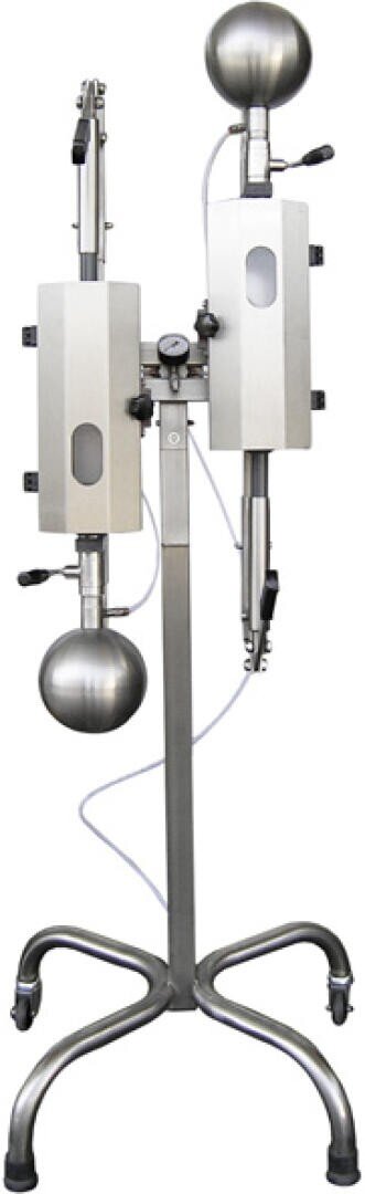 Laboratory distillation apparatus made of metal with two round bottom flasks, vertical glass tubes and control valves, mounted on a mobile stand.